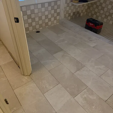 Newly installed beige and gray marble floor tiles in a bathroom under renovation with checkered wall tiles.