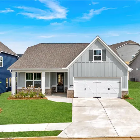 Modern single-family house with gray siding, white garage door, and neatly landscaped green lawn under a blue sky