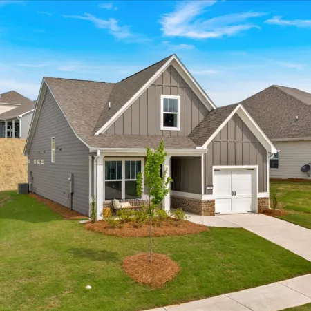 Modern single-family home with gray siding, a small front porch, and a manicured lawn under a clear blue sky.