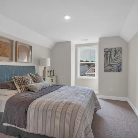 Bright modern bedroom with large bed, blue upholstered headboard, textured pillows, and natural light from a window.