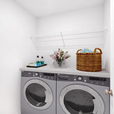 Bright laundry room with modern appliances, decorative basket, and shelf storage for cleaning supplies.
