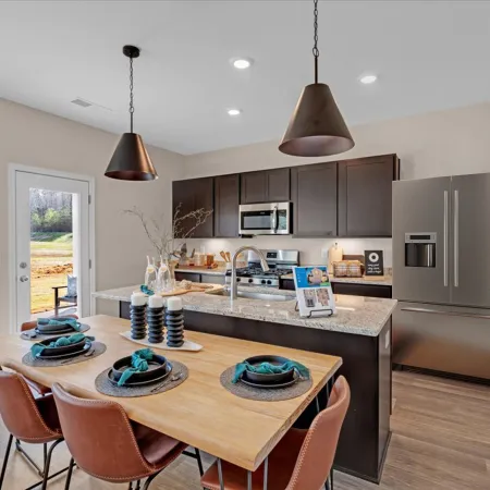 Modern kitchen with wooden dining table, black cabinetry, and stylish pendant lighting, showcasing sleek appliances.