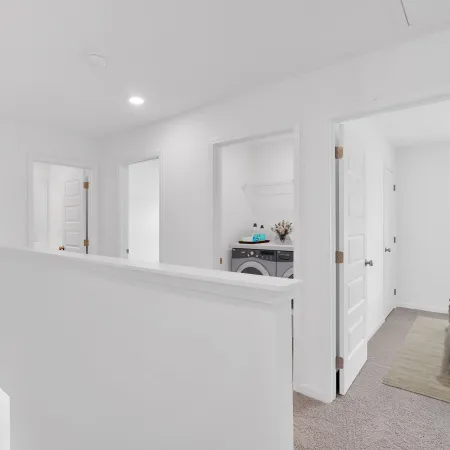 Bright, modern hallway with laundry room and bedrooms in a stylish home interior.