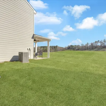 View of a home exterior with a grassy yard and clear blue sky in the background.