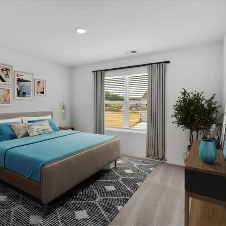 Bright modern bedroom with a blue bedspread, artwork, and natural light from a large window.