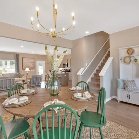 Stylish dining area with green chairs, a chandelier, and tasteful decor in a modern home.