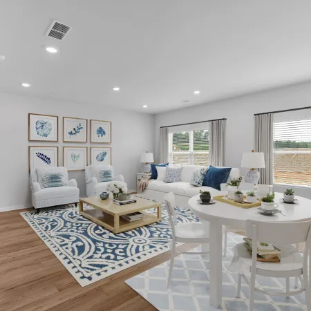 Bright and stylish living room with blue accents, white furniture, and large windows for natural light.