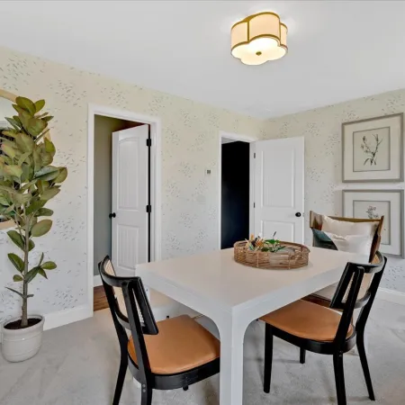 Modern dining room with white table, black chairs, patterned wallpaper, potted plant, and wall art.