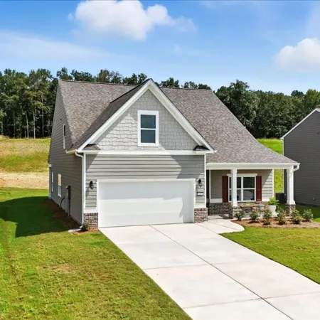 Modern two-story suburban house with gray siding, attached garage, and well-kept lawn on sunny day