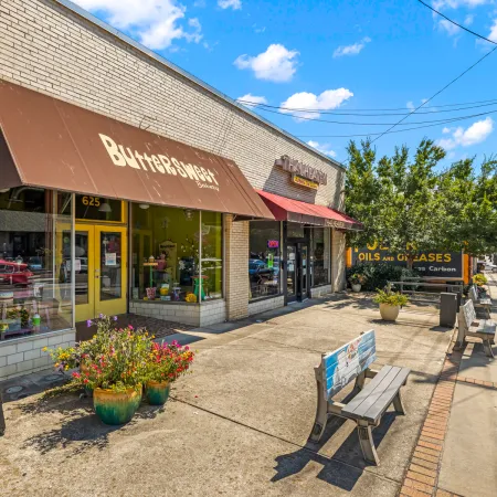 a sidewalk with a bench and a storefront