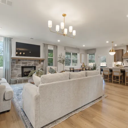 Spacious open-concept living room and kitchen with neutral furniture, hardwood floors, and modern lighting fixtures