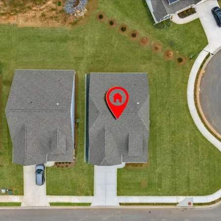 Aerial view of residential homes with a prominent location marker on one house.