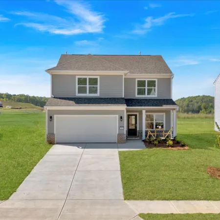 Beautiful two-story house with a green lawn and clear blue sky in a suburban neighborhood.