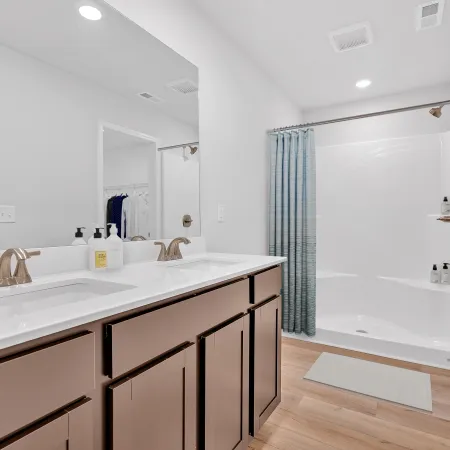 Elegant modern bathroom with double sinks, neutral colors, and a spacious shower area.