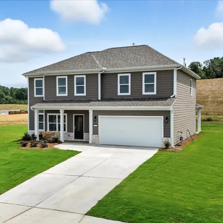 Modern two-story gray house with white garage door and well-maintained green lawn on sunny day