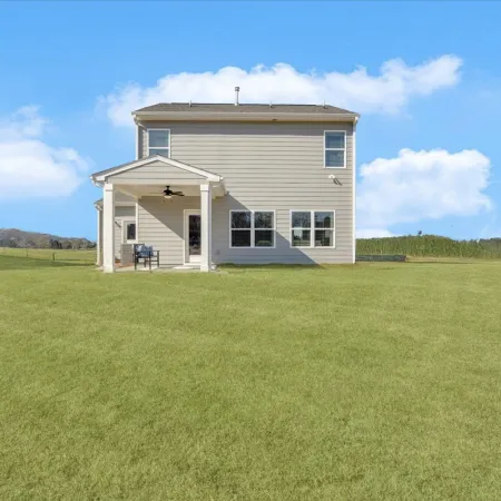 Spacious backyard view of a modern two-story home on a sunny day.