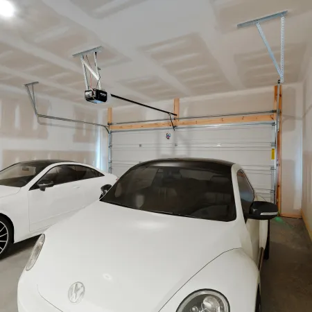 Two white cars parked inside a clean, unfinished garage with drywall and a closed garage door.