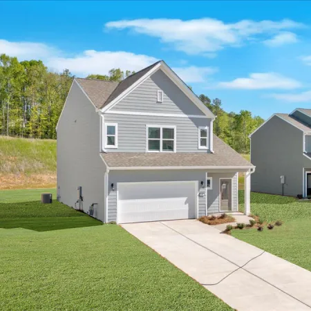 Newly built single-family homes with green lawns and clear blue skies in a suburban neighborhood.