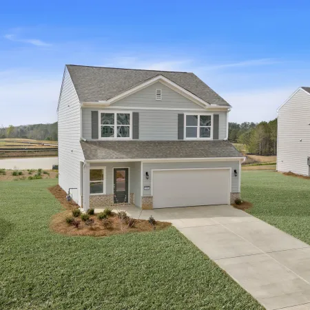 Modern two-story house with gray siding, attached garage, and well-maintained lawn under a blue sky