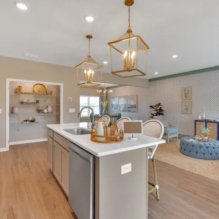 Modern kitchen with island, elegant lighting, and stylish decor in a spacious living area.