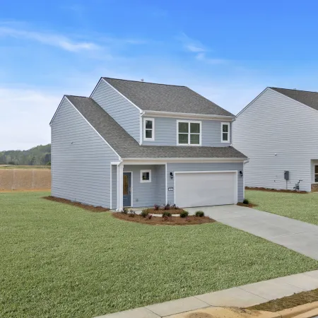 Newly built homes with modern architecture and green lawns under a clear blue sky.