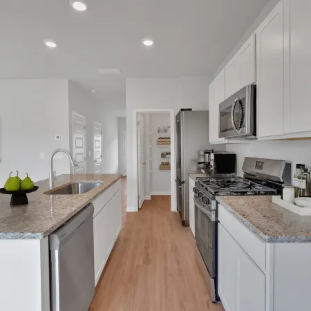 Modern kitchen with white cabinets, granite countertops, stainless steel appliances, and wood flooring