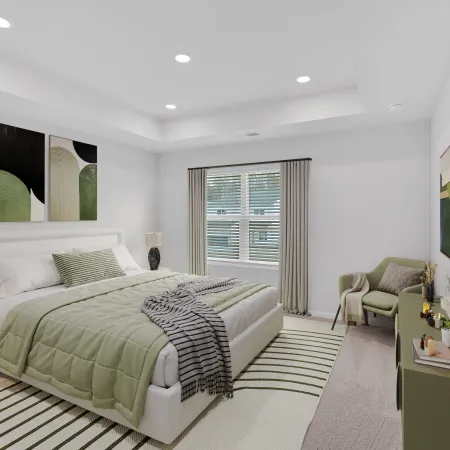 Modern bedroom with green and white decor featuring a bed, armchair, lamps, and window with curtains.