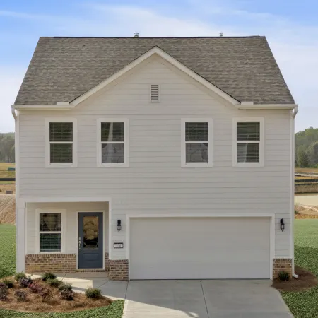 Two-story white house with double garage and blue front door on a newly developed grassy lot.