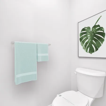 Stylish bathroom corner with white walls, plant artwork, and mint-colored towels next to a toilet.