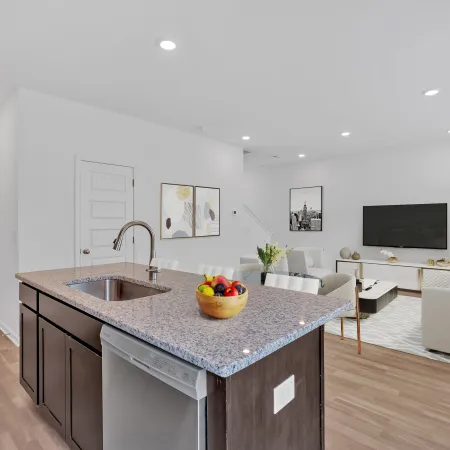 Bright modern kitchen with granite island, living area featuring stylish furniture and decor.