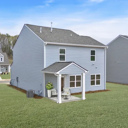 Modern gray house with porch, green lawn, and blue sky in a tranquil neighborhood setting.