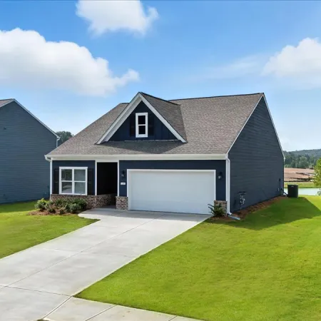 Modern gray suburban house with a two-car garage, manicured lawn, and clear blue sky background