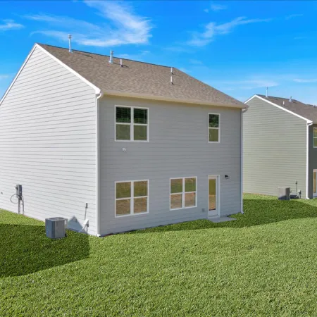 Modern house exterior with landscaped yard and clear blue sky, showcasing neighborhood architecture.