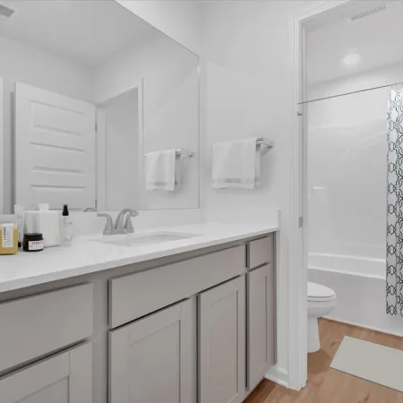 Modern bathroom with sleek white cabinetry, toiletries, and a stylish shower curtain.