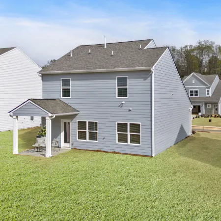 Newly built gray homes with green lawns in a residential neighborhood setting.