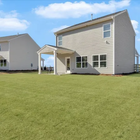 Two modern houses with spacious yards under a blue sky, showcasing a suburban landscape.