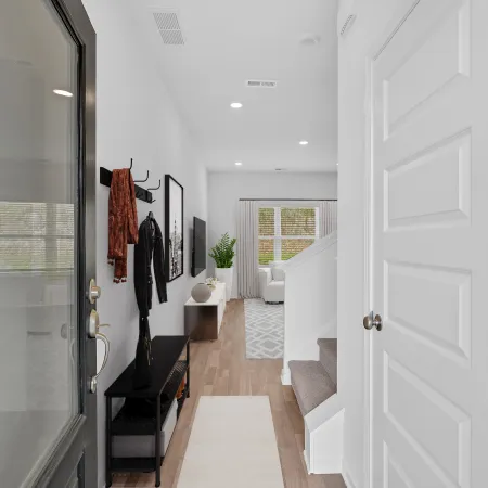 Bright modern hallway with stairs, stylish decor, and natural light streaming through windows.