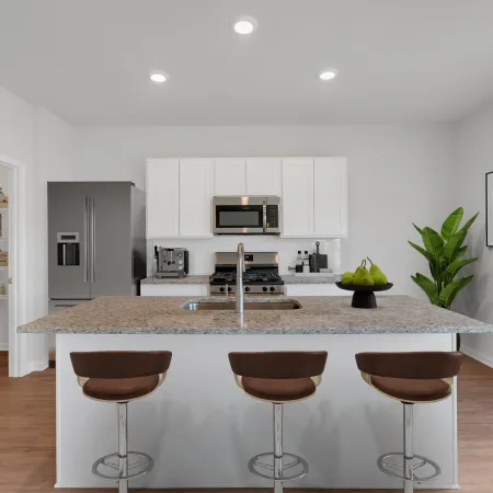 Modern kitchen with granite island, three bar stools, stainless steel appliances, and minimalist decor with plants.