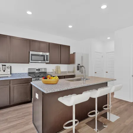 Modern kitchen featuring dark cabinets, a granite island, and sleek bar stools for contemporary design.