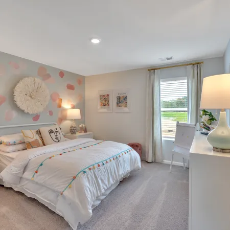Brightly decorated bedroom with soft pastel wall art and cozy furnishings, perfect for relaxation.