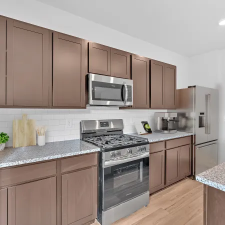 Modern kitchen with stainless steel appliances and wooden cabinets, featuring a granite countertop.
