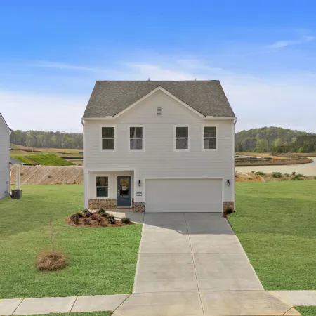 Modern two-story white house with attached garage and green lawn on a clear day with blue sky.
