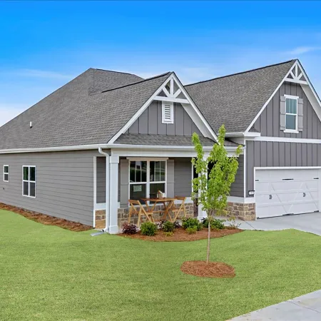 Modern gray suburban house with a two-car garage, front porch, and neatly manicured lawn under blue sky.