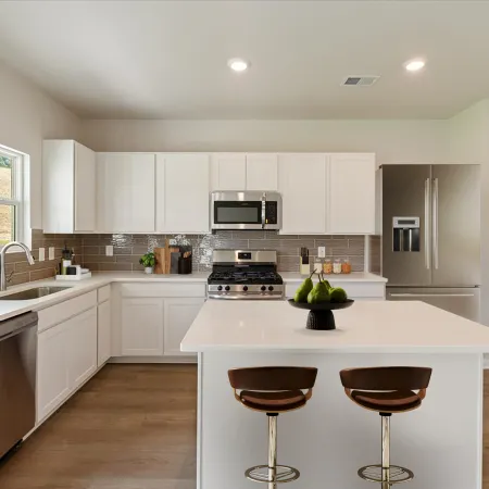 Modern kitchen with white cabinets, stainless steel appliances, a large island, and brown wooden stools under bright lighting.