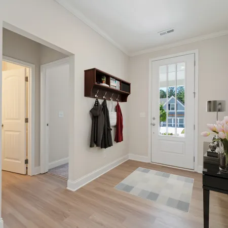 a room with white walls and a wood floor with a black table and a vase with flowers and