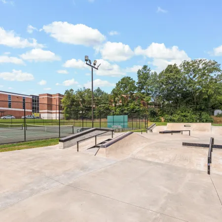 a concrete area with a fence and trees in the background