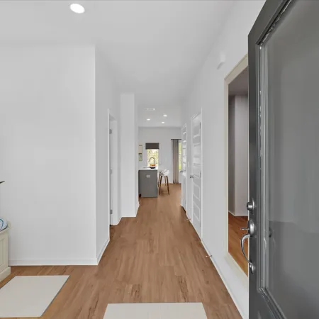 Bright hallway with wooden flooring, modern decor, and an open layout leading to a kitchen area.