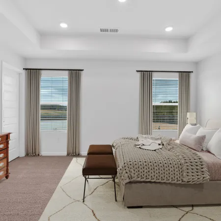 Spacious bedroom with tufted bed, chunky knit blanket, wooden dresser, and large windows with beige curtains.