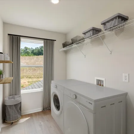 Bright laundry room with white washer and dryer, wall shelves, wire basket, window with curtains, and wood flooring