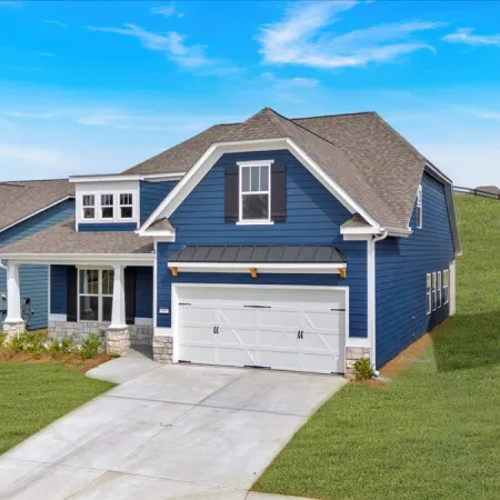 Modern blue two-story house with white garage door, concrete driveway, and green lawn under clear blue sky.